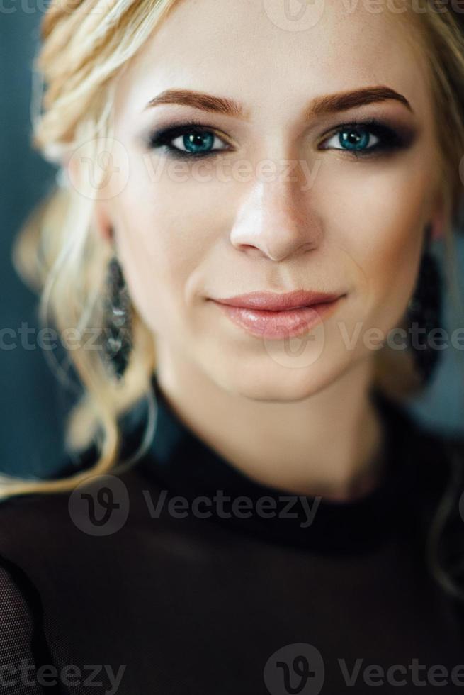 Blonde girl with blue eyes in a black dress photo