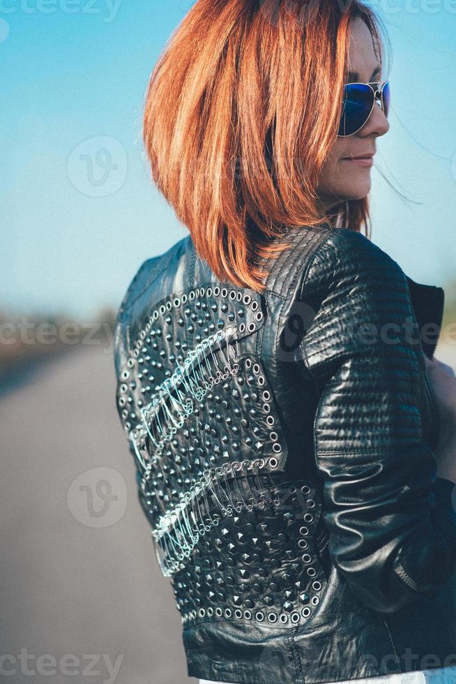 chica pelirroja con una chaqueta negra y gafas azules foto