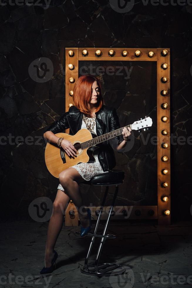 chica joven con el pelo rojo con una guitarra acústica foto