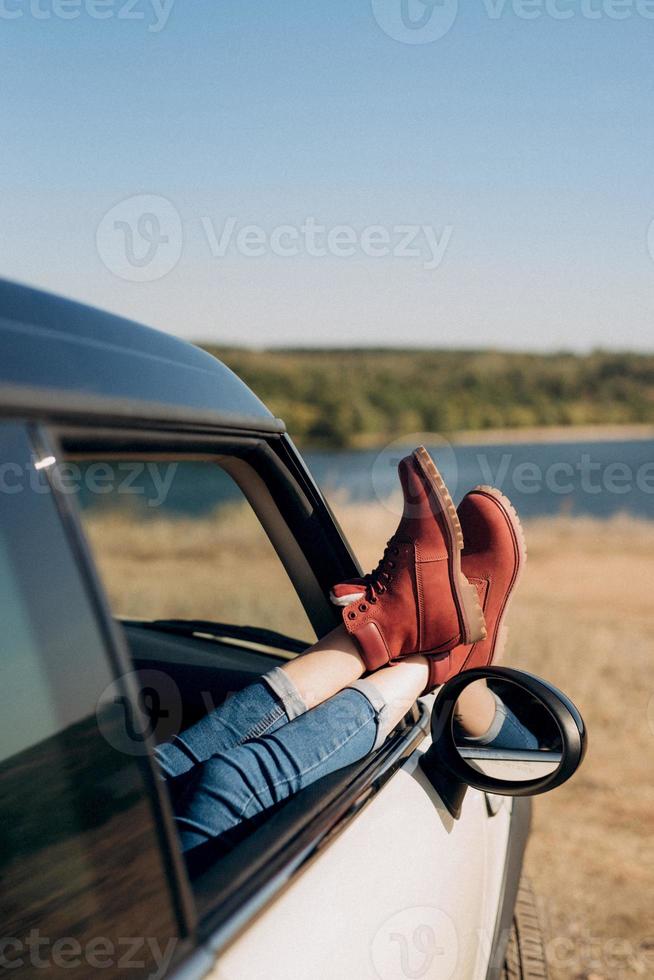 Chica rubia con coletas en una camisa, jeans, zapatos rojos y gafas negras. foto