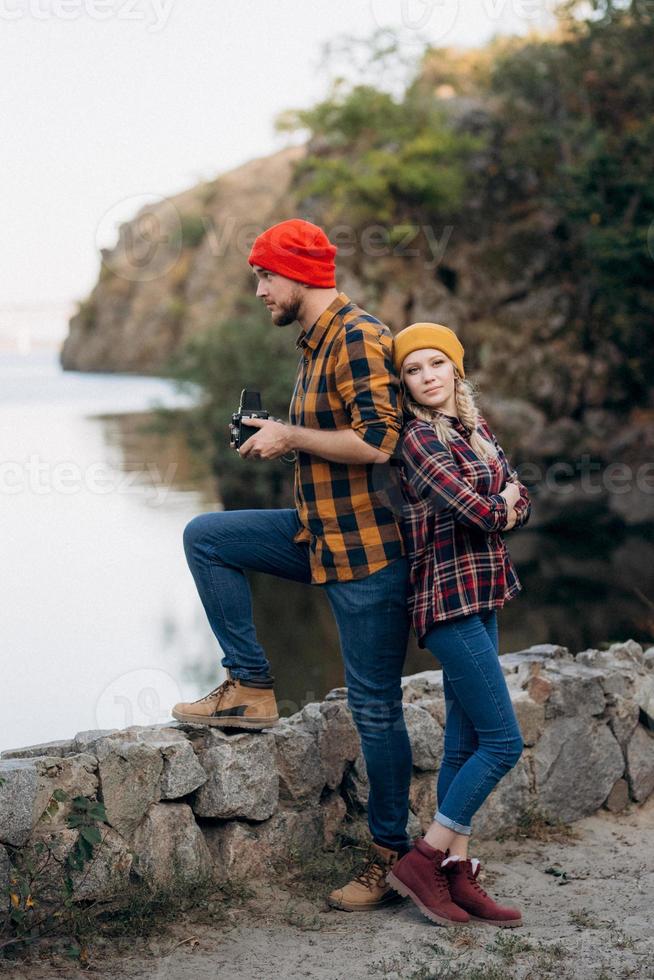 Bald guy with a beard and a blonde girl in bright hats are taking pictures with an old camera photo