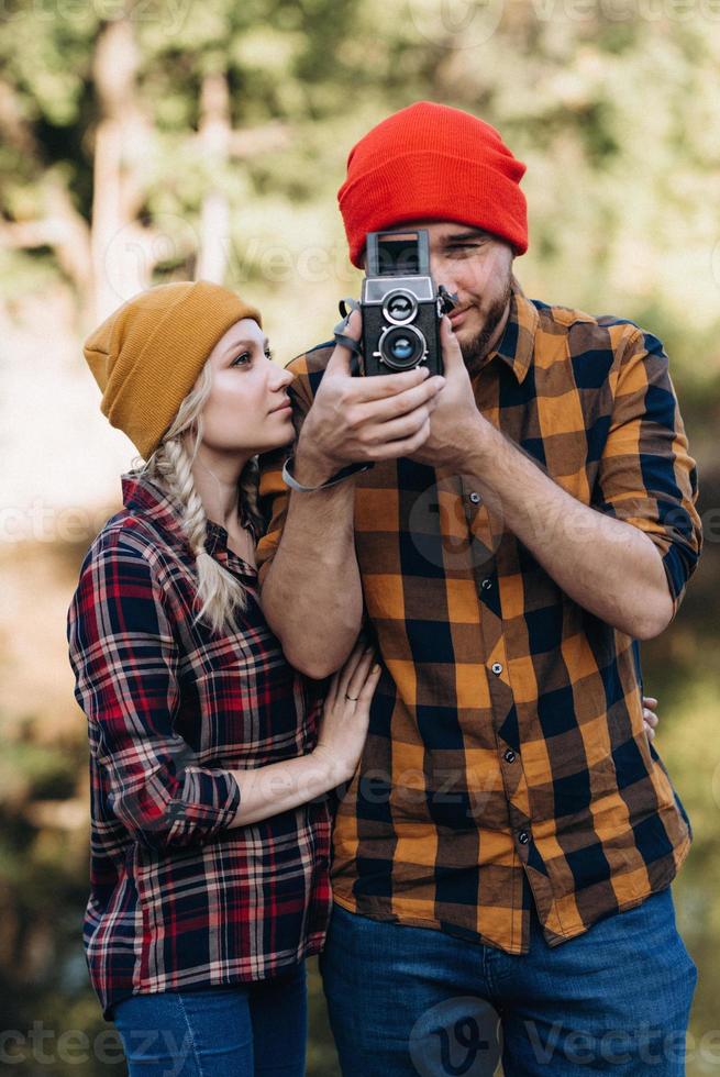 Bald guy with a beard and a blonde girl in bright hats are taking pictures with an old camera photo