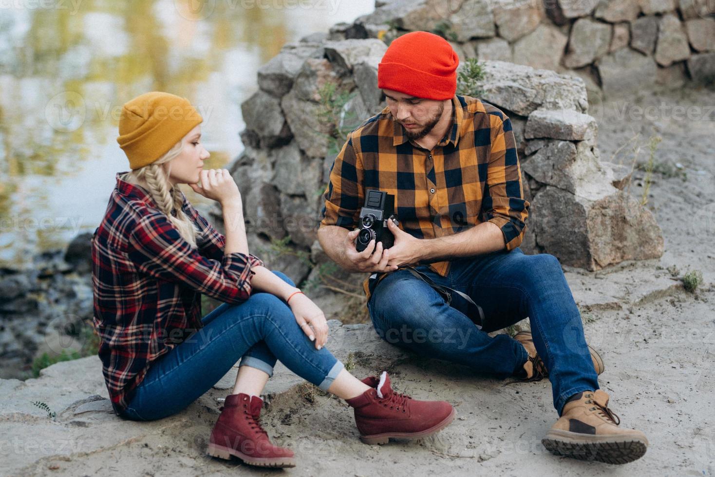 Chico calvo con barba y una chica rubia con sombreros brillantes están tomando fotografías con una cámara vieja foto