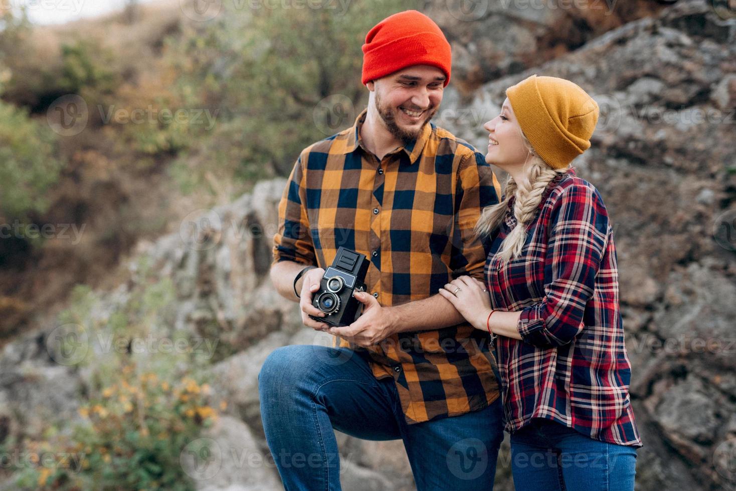 Bald guy with a beard and a blonde girl in bright hats are taking pictures with an old camera photo