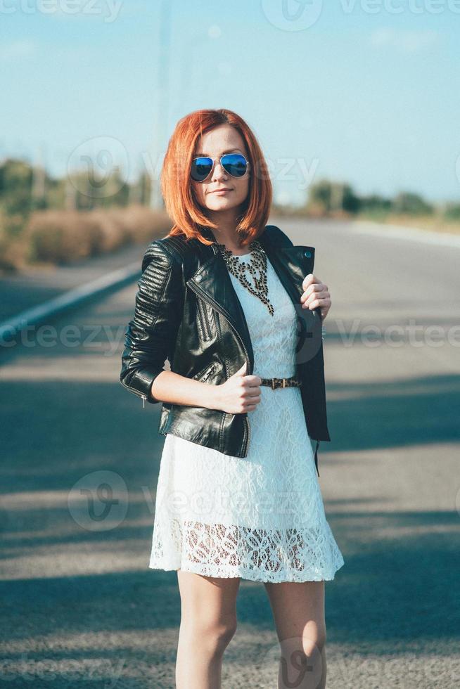 red haired girl in a black jacket and blue glasses photo