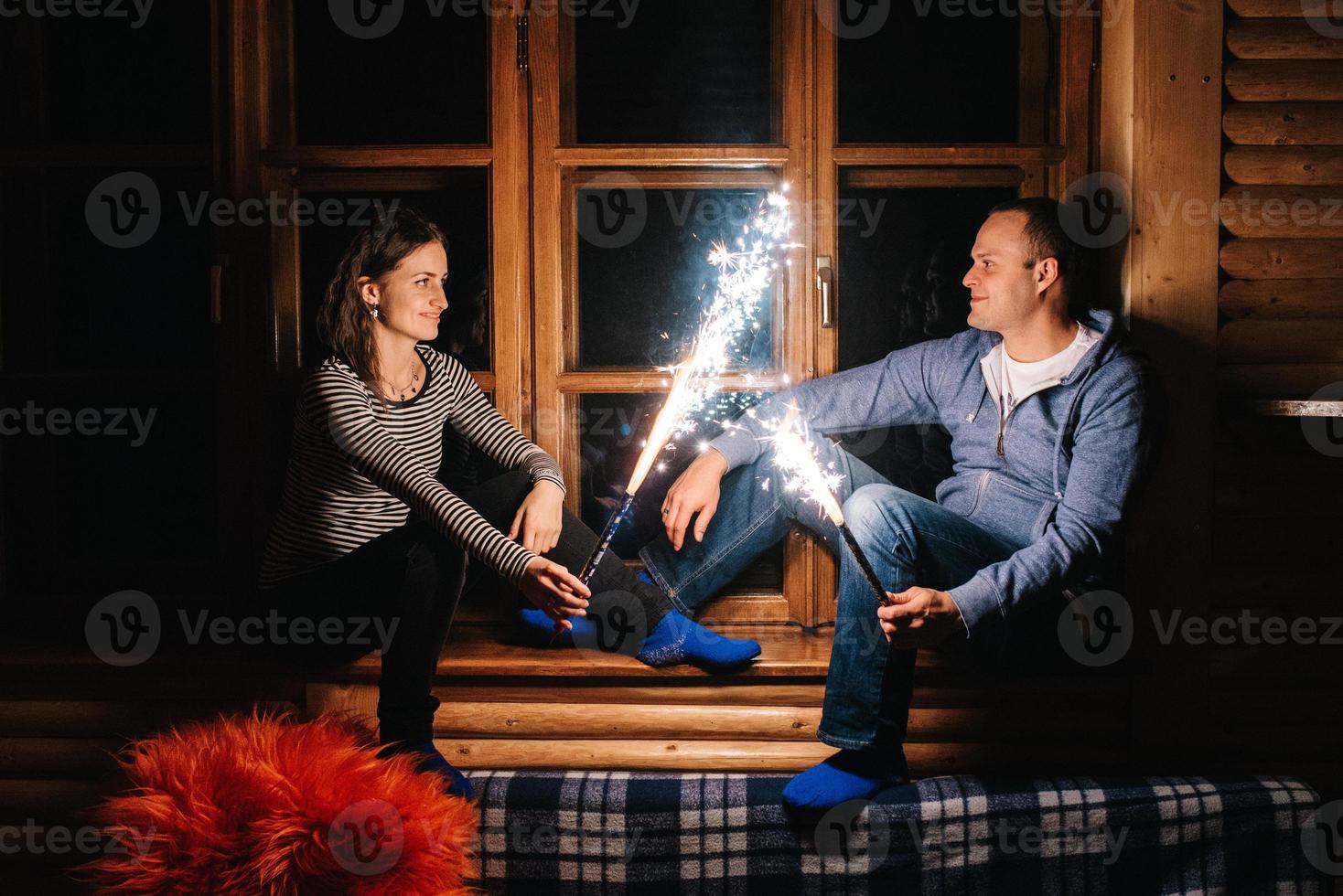 chico y una chica encendieron bengalas dentro de una casa de madera foto
