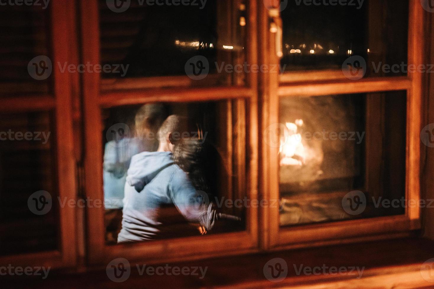 chico y chica están sentados en el fondo de una chimenea encendida foto