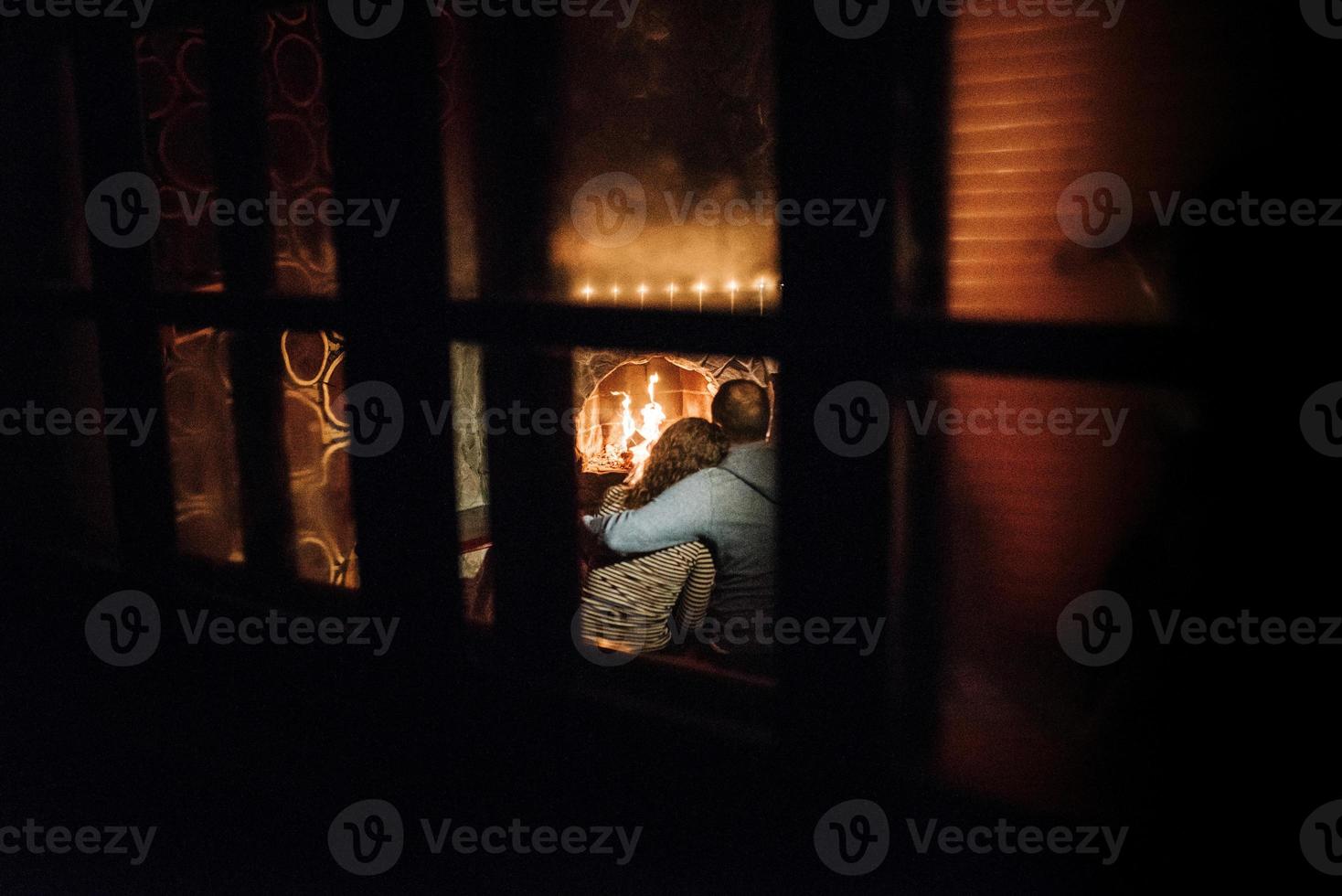 guy and girl are sitting on the background of a burning fireplace photo