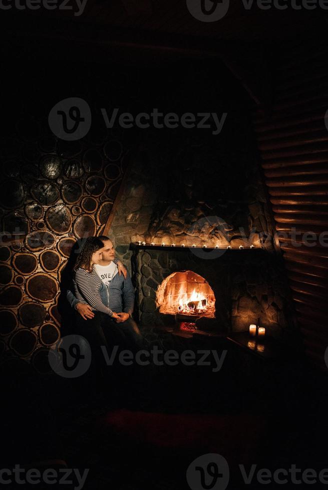 guy and girl are sitting on the background of a burning fireplace photo