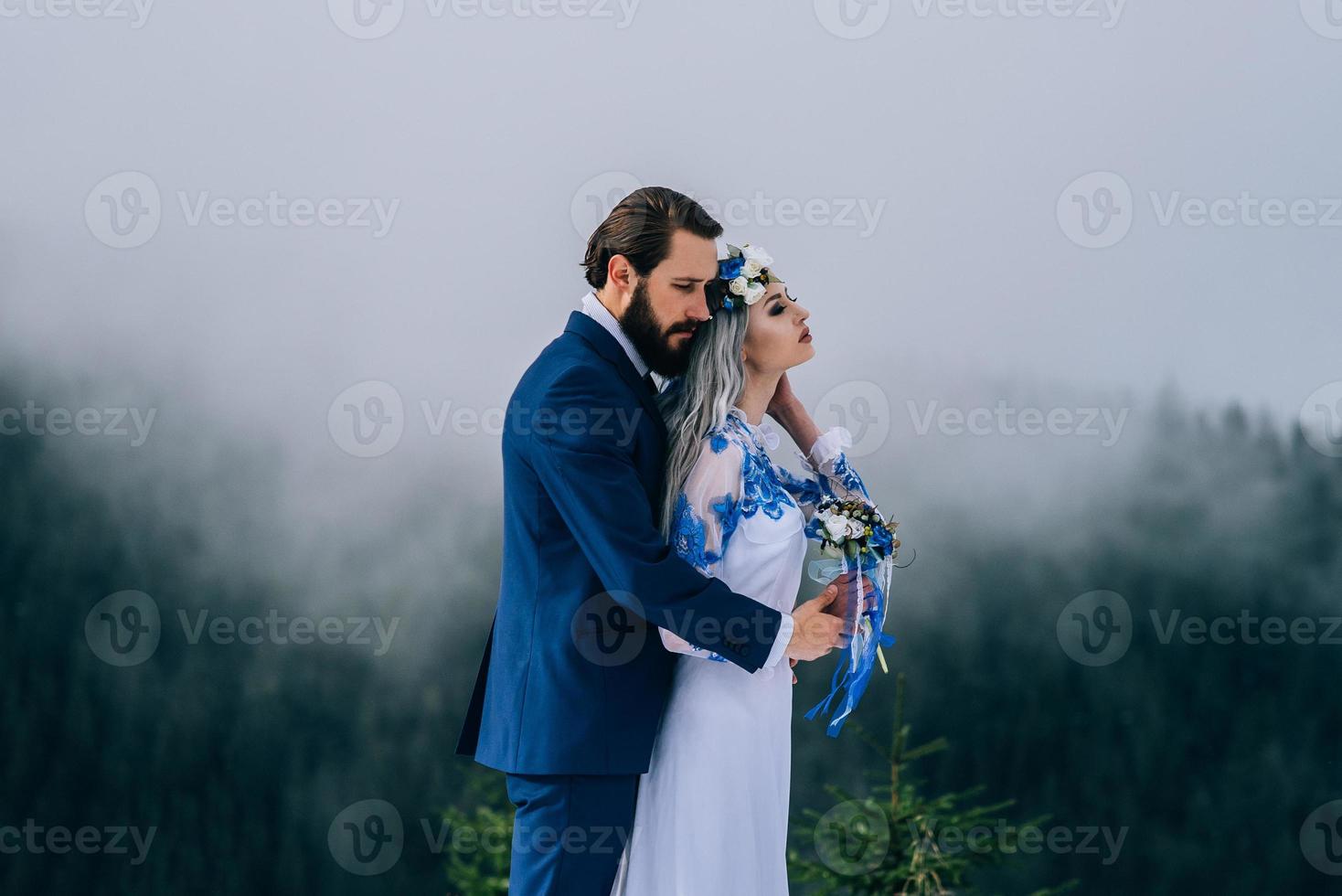 El novio en un traje azul y la novia en blanco en las montañas de los Cárpatos. foto