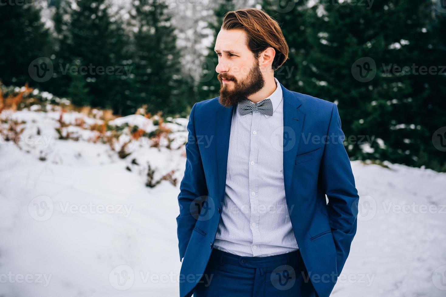 El novio con un traje azul en los Cárpatos de las montañas foto