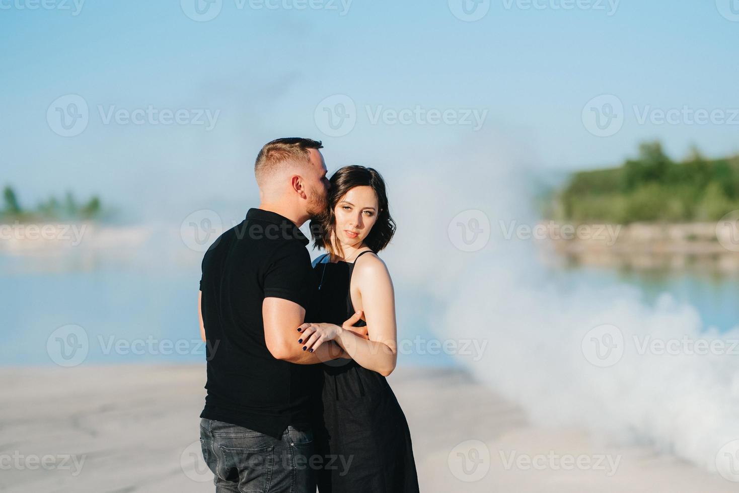 chico y una chica vestidos de negro se abrazan dentro de un humo foto