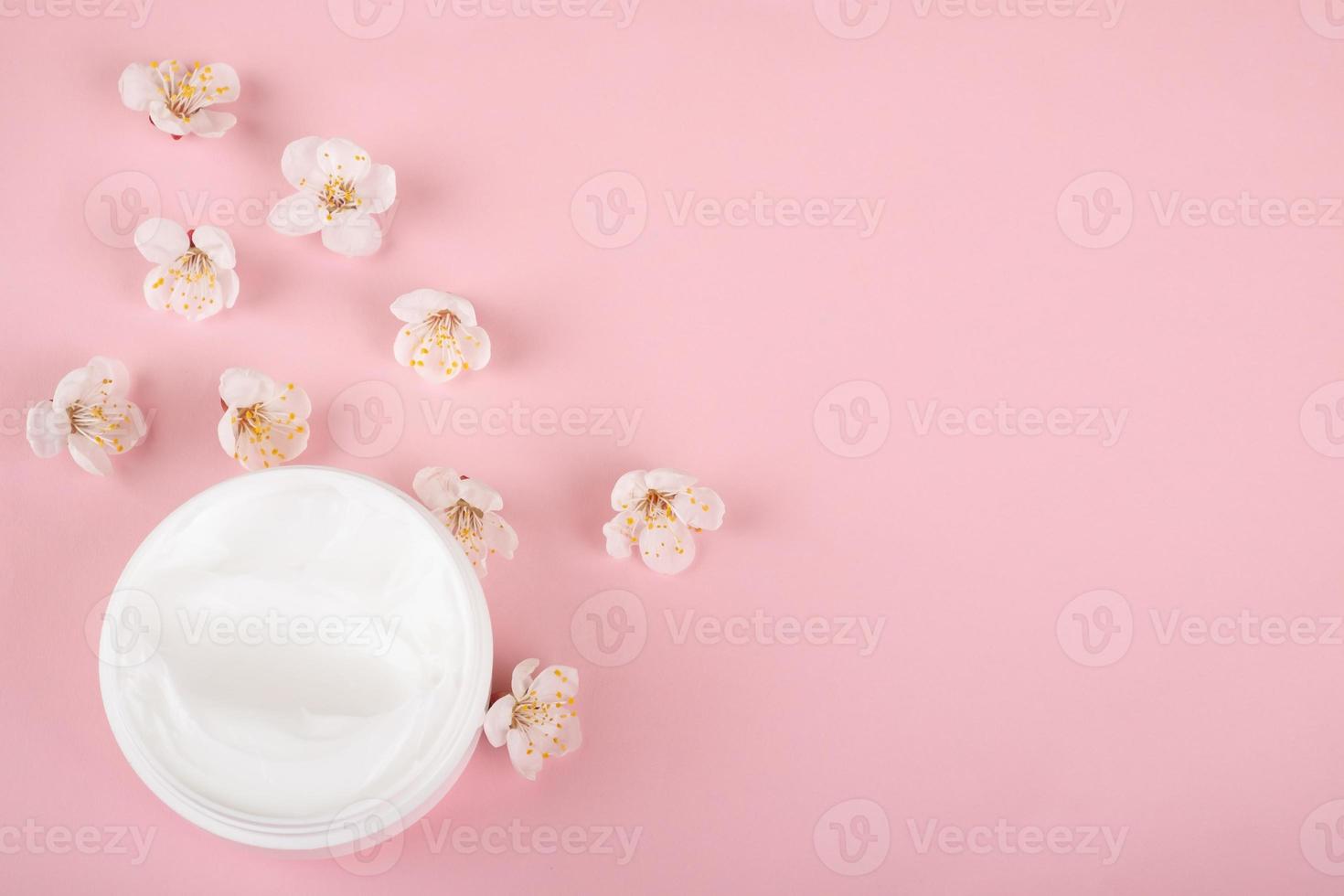 Crema y flores sobre fondo rosa, belleza cosmética para el cuidado de la piel con espacio de copia foto