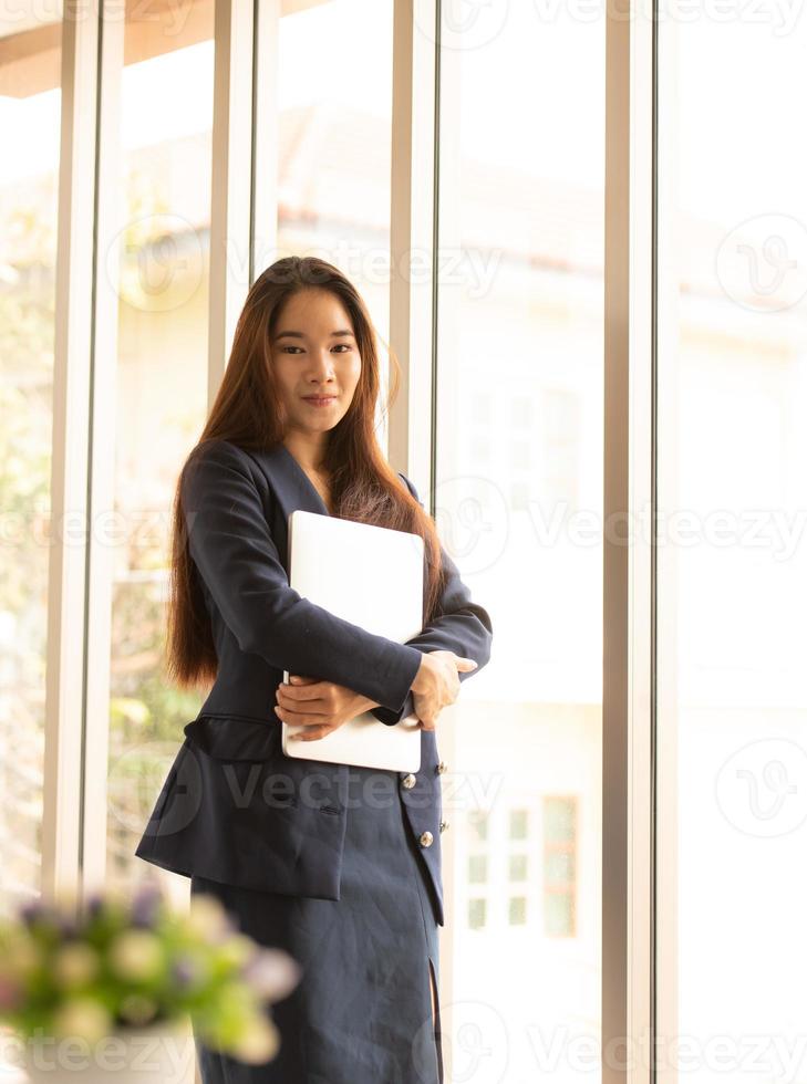 mujer de negocios asiática, tenencia, computadora portátil foto