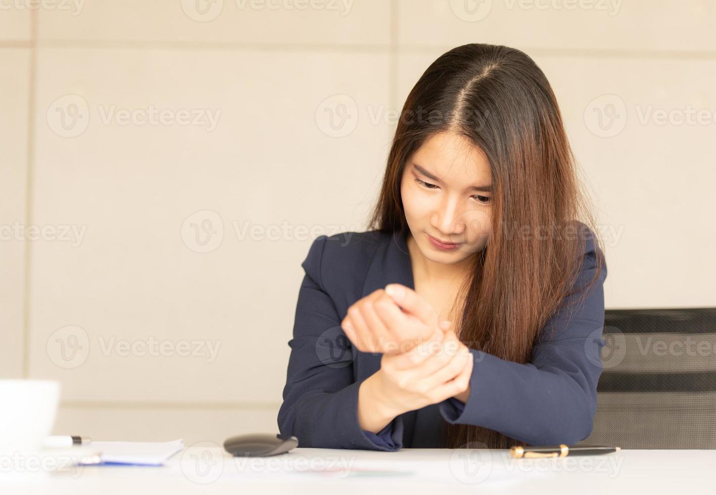 Asian business woman holding her wrist pain from working and using computer. Office syndrome photo