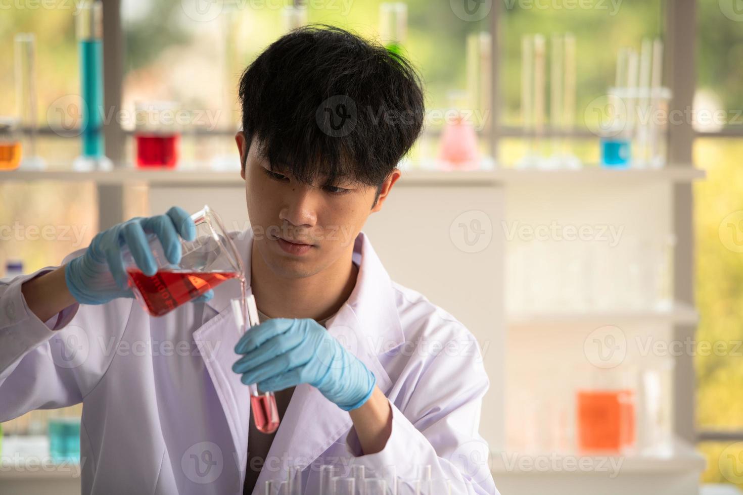 Joven científico asiático pruebas de laboratorio y análisis de productos químicos en el laboratorio foto