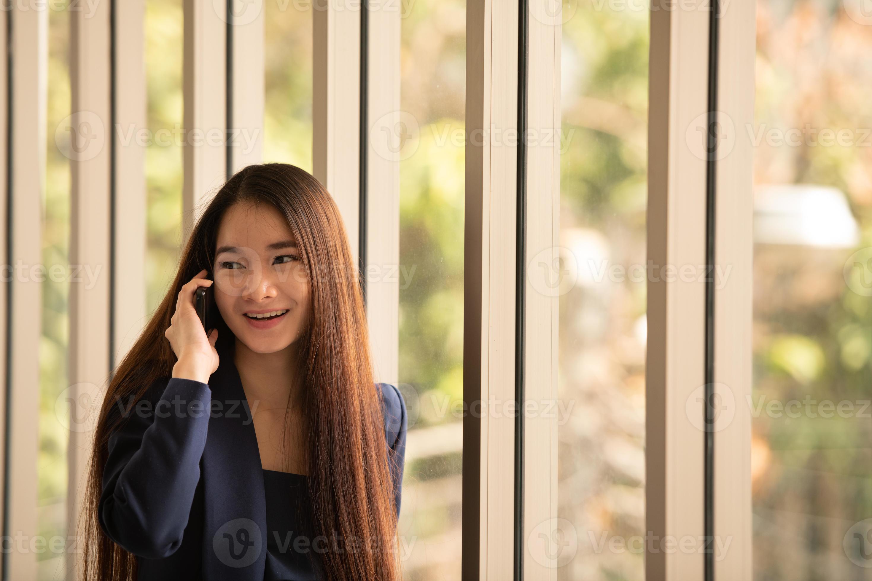 Mujer de negocios asiática mediante teléfono móvil en una oficina. foto