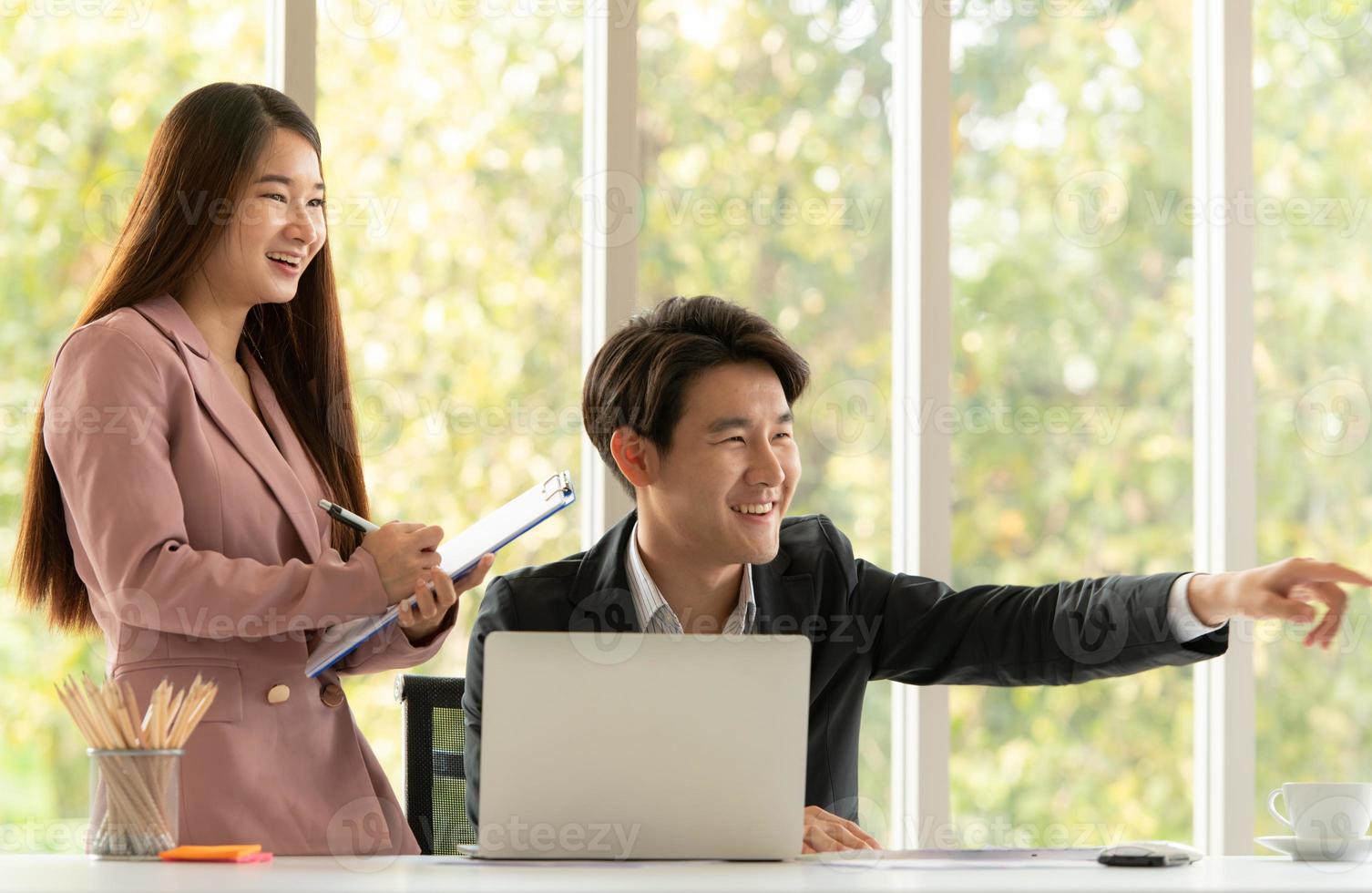 Young Asian businessman and businesswoman work in an office setting with natural background photo