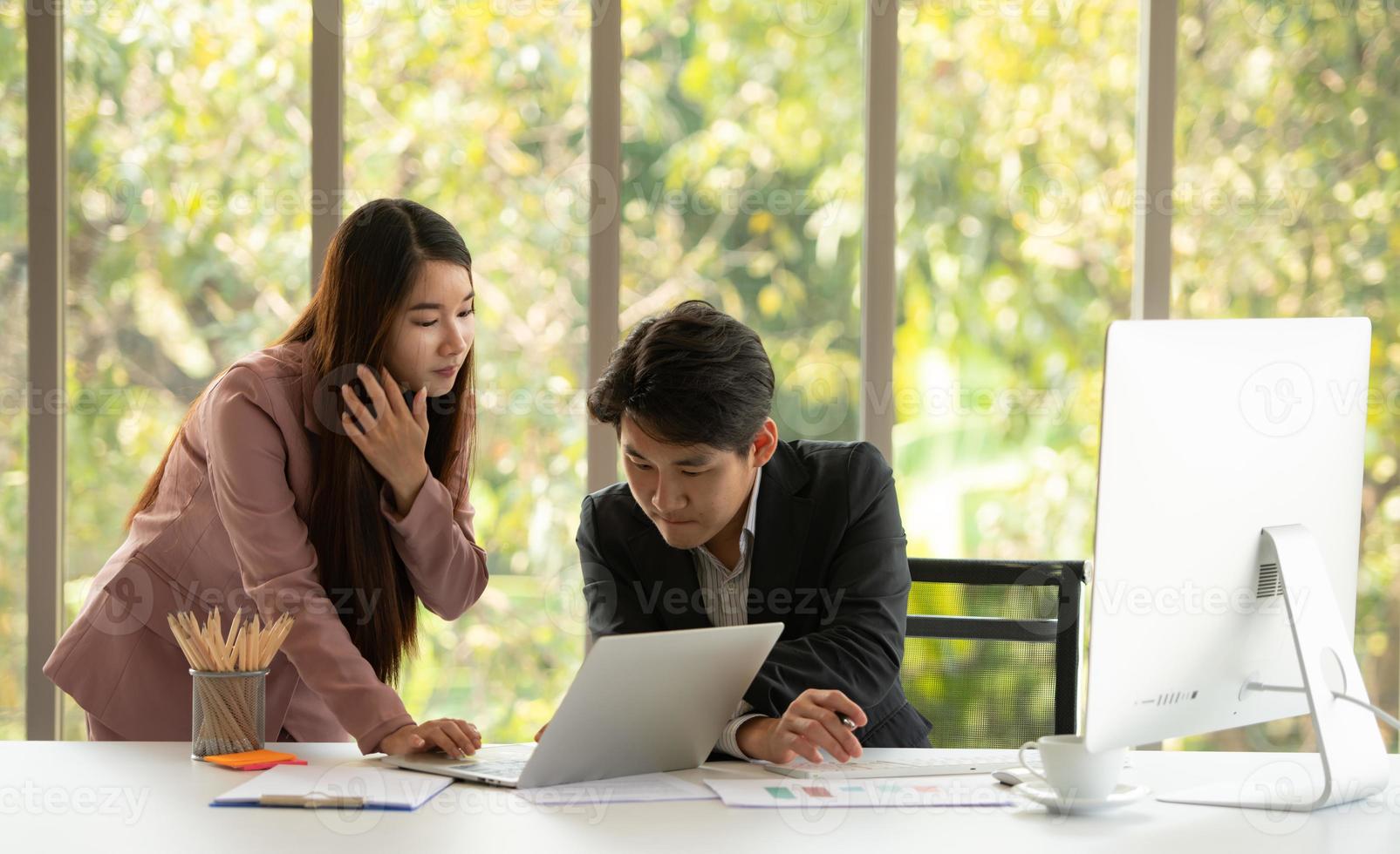 Young Asian businessman and businesswoman work in an office setting with natural background photo