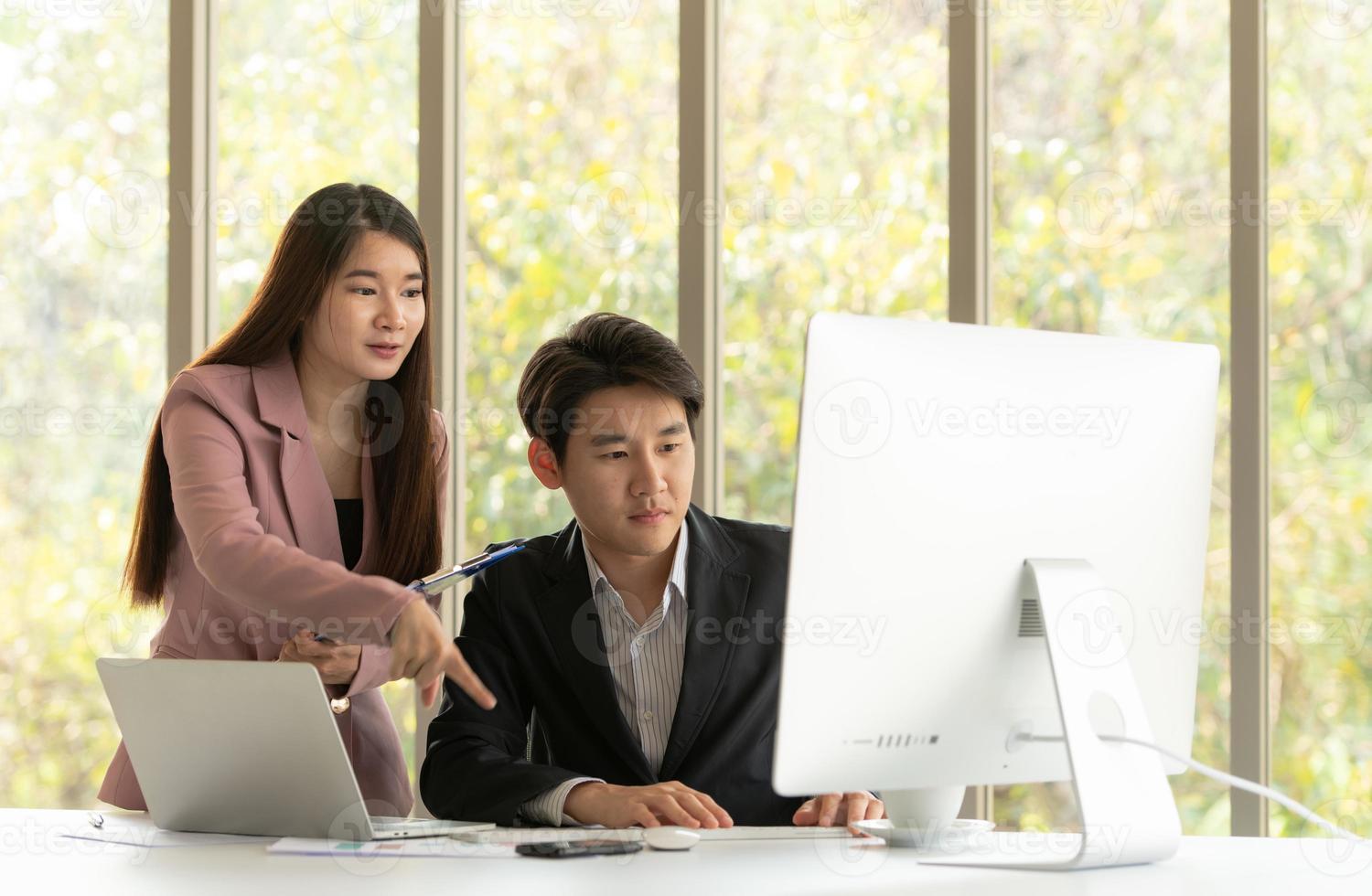 Young Asian businessman and businesswoman work in an office setting with natural background photo