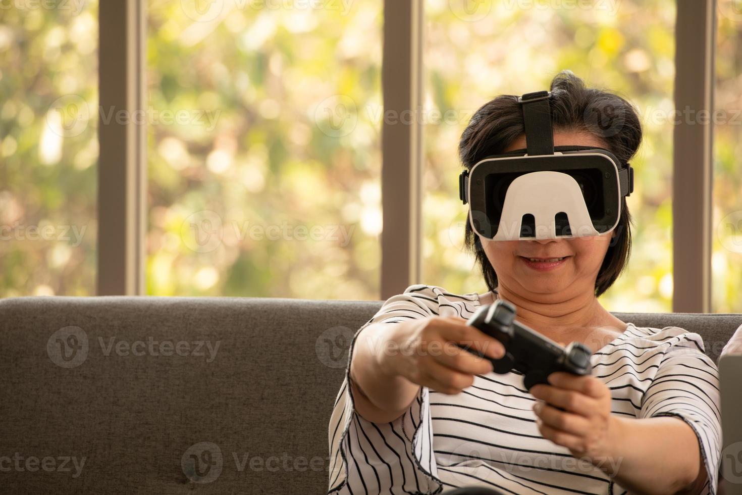 Senior Asian woman using a virtual reality goggle system in the natural living room background with modern technology photo