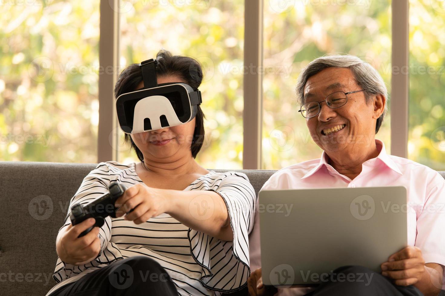 Senior hombre y mujer asiáticos se relajan de vacaciones en el fondo natural de la sala de estar con tecnología moderna foto