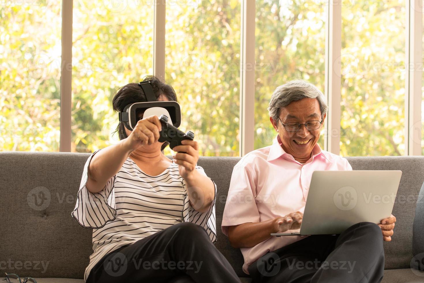 Senior hombre y mujer asiáticos se relajan de vacaciones en el fondo natural de la sala de estar con tecnología moderna foto