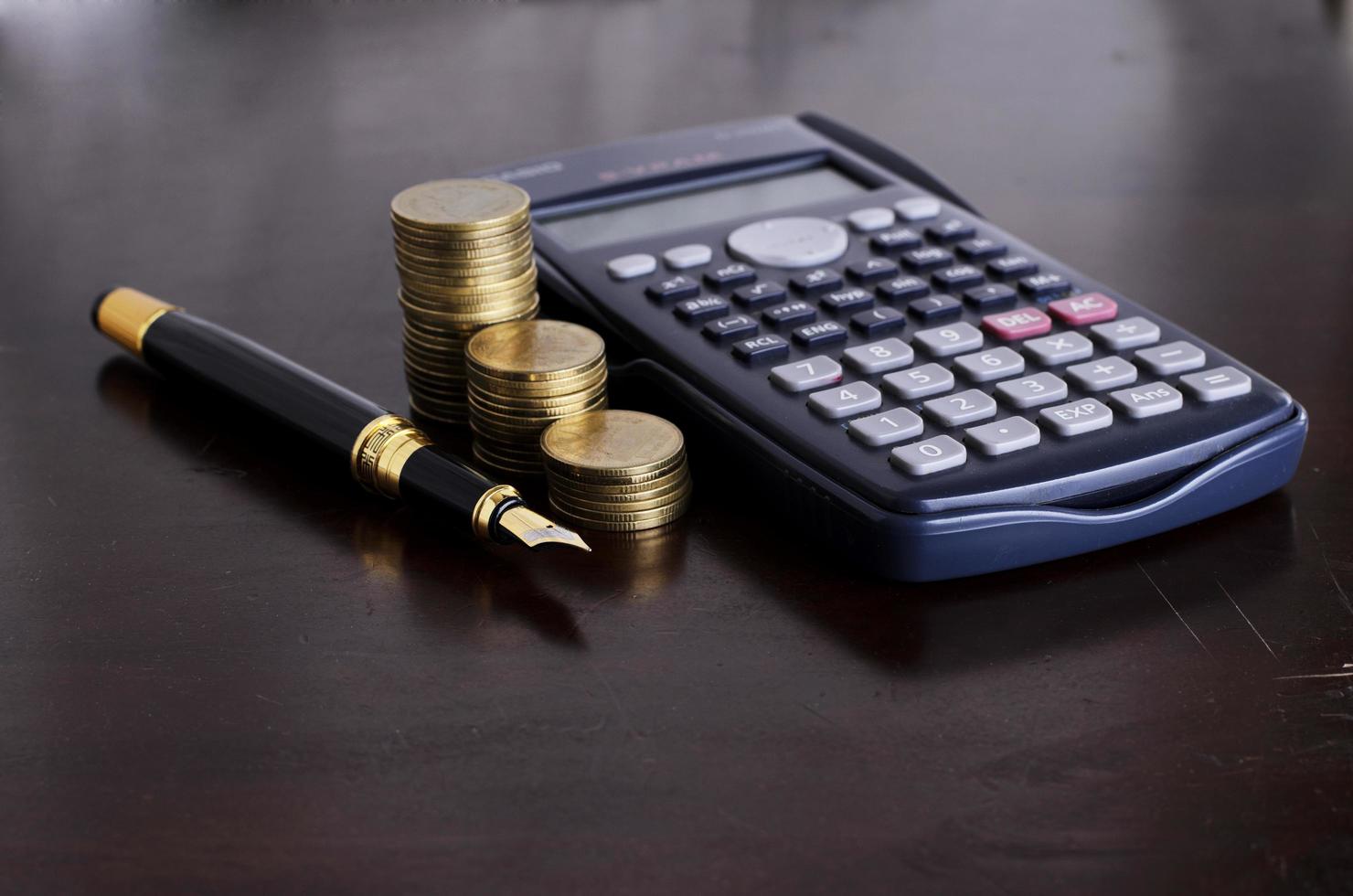 Business and Finance concept with Fountain pen and Calculator money coins stack photo