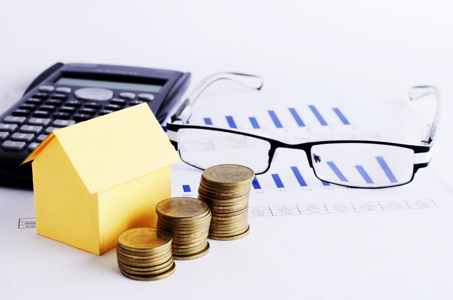 Home loans concept with coins stack and house paper calculator and eyeglass photo