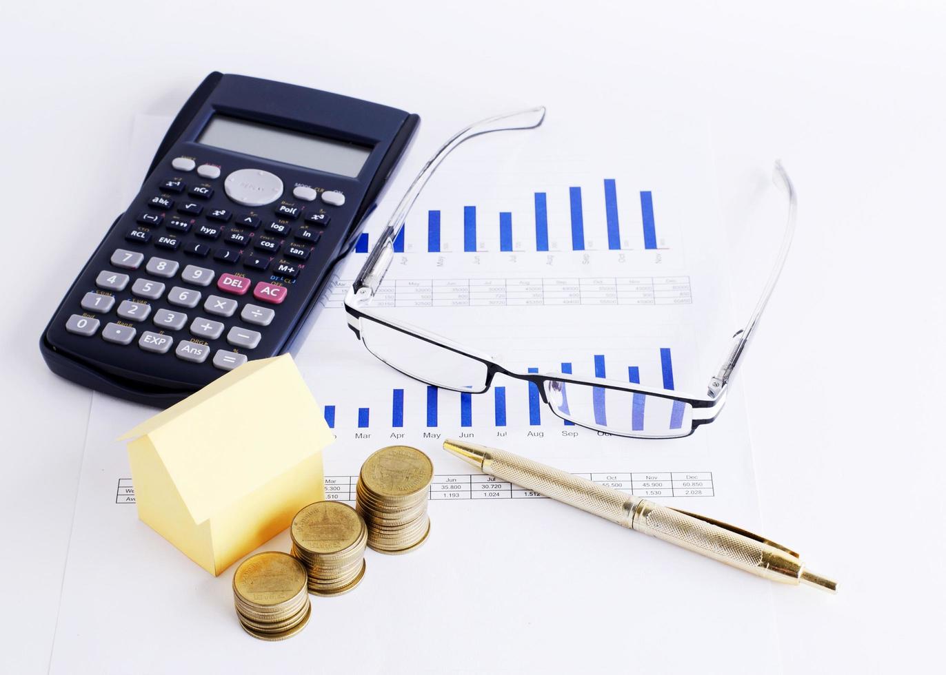 Housse paper and coins stack with Eyeglass and Calculator and pen on Chart for Loans money concept photo