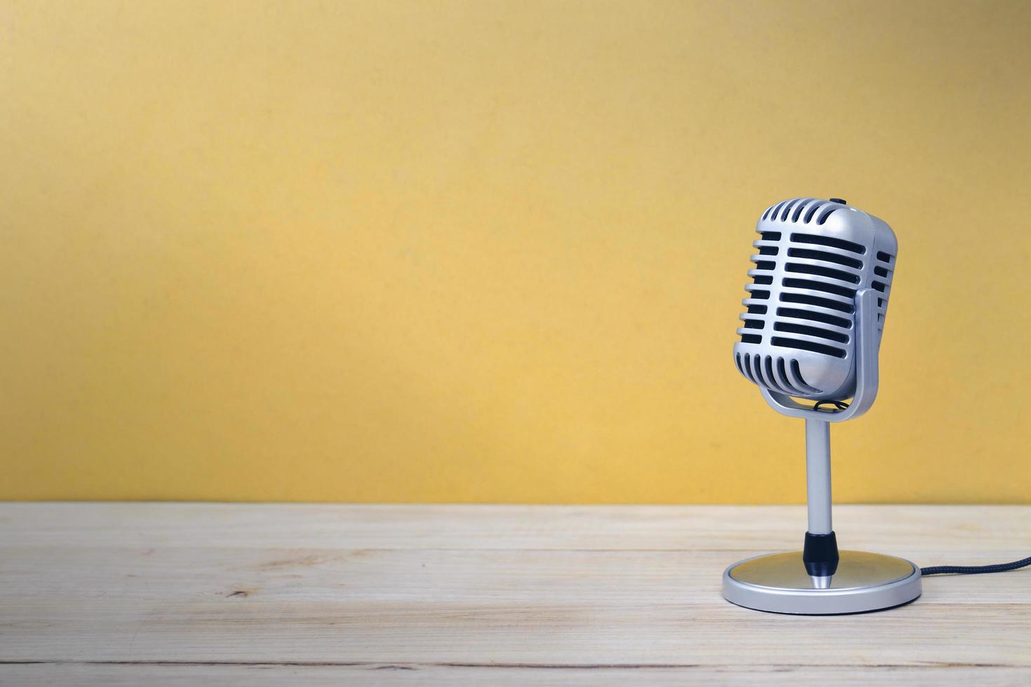 Vintage microphone isolated on wooden and yellow background photo