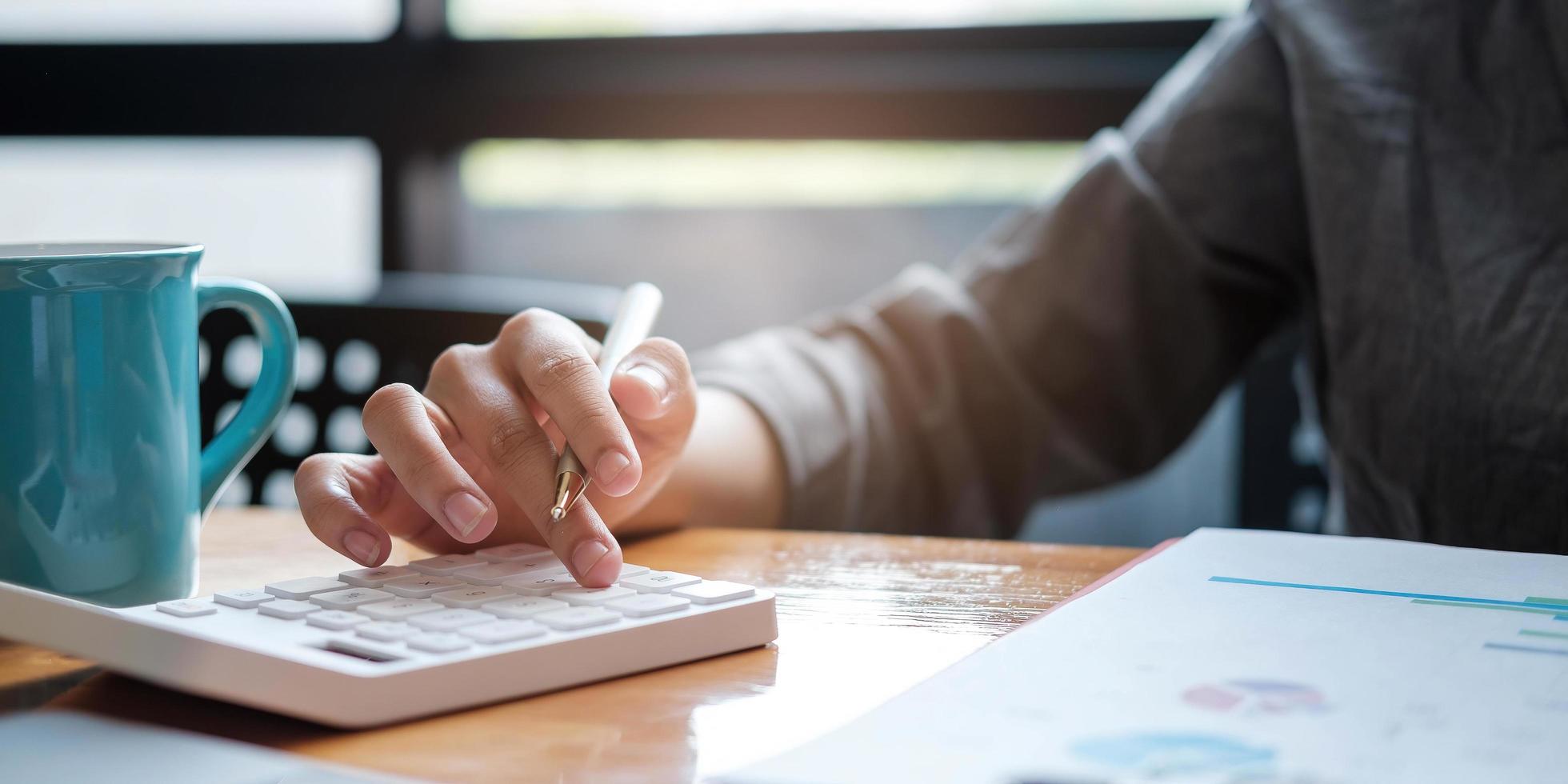 a businesswoman uses a laptop to calculate investment results. And making financial reports on the desk Business finance accounting concept photo