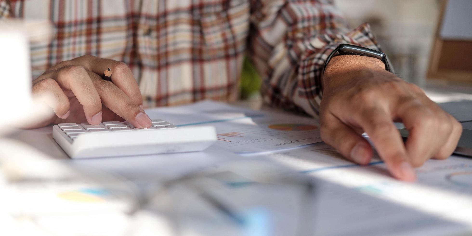 Businessman hands holding pen working on calculator and financial paperwork. photo