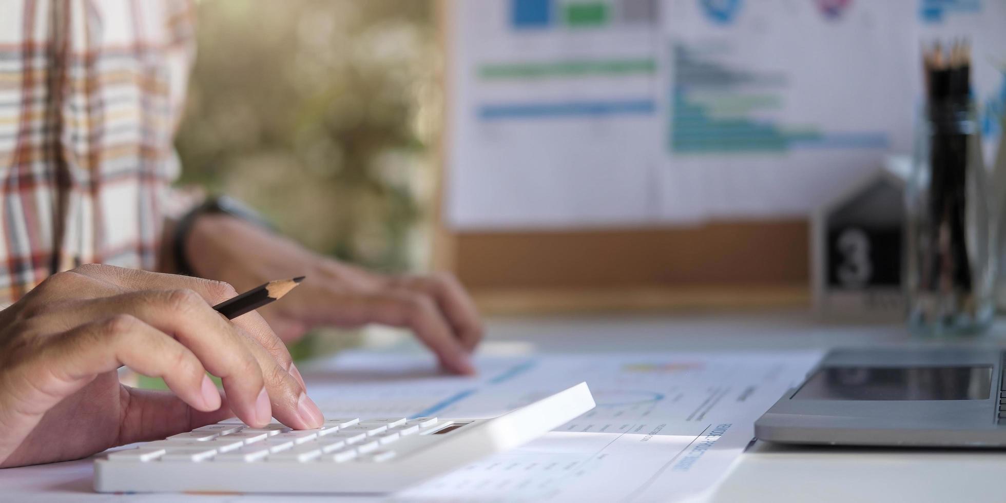 Close-up Of A Businessman Calculating Invoice Using Calculator At Workplace photo