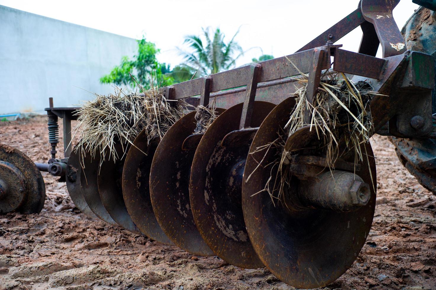 Cerca de gradas de discos en la parte trasera de un tractor. Cuchillas de acero sucias de un tractor con tierra y paja seca foto