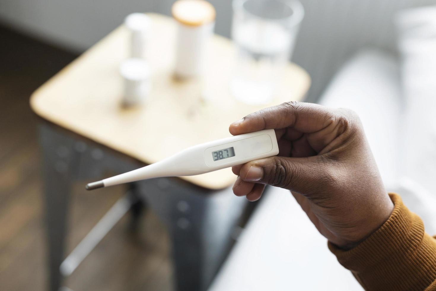 persona que controla su temperatura con un termómetro foto