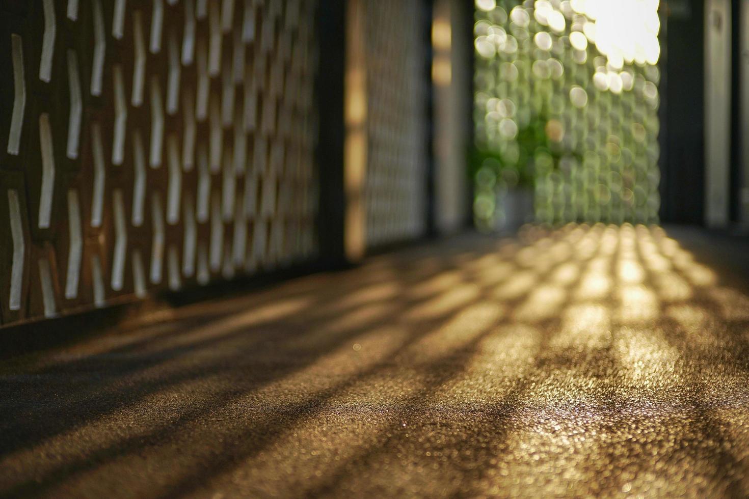 El enfoque selectivo en el piso de cemento del corredor que refleja la luz de una puesta de sol con fondo de luces bokeh borrosa. foto