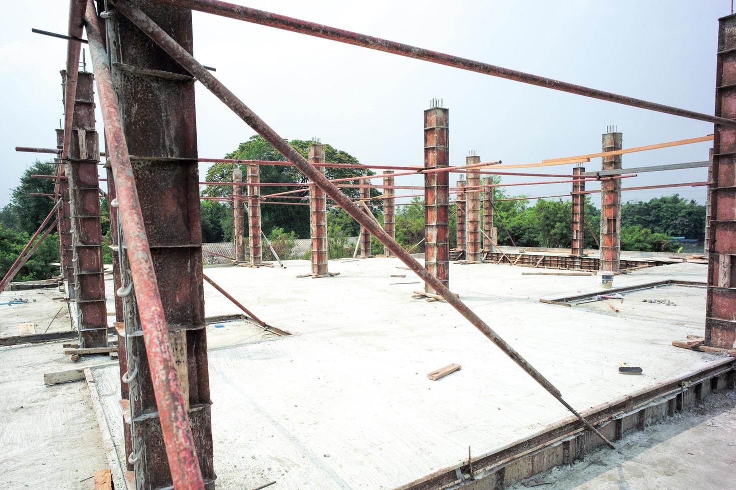 Perspectiva de columnas de hormigón en el modelo de acero de pie sobre el piso de cemento en el sitio de construcción con fondo de cielo despejado foto