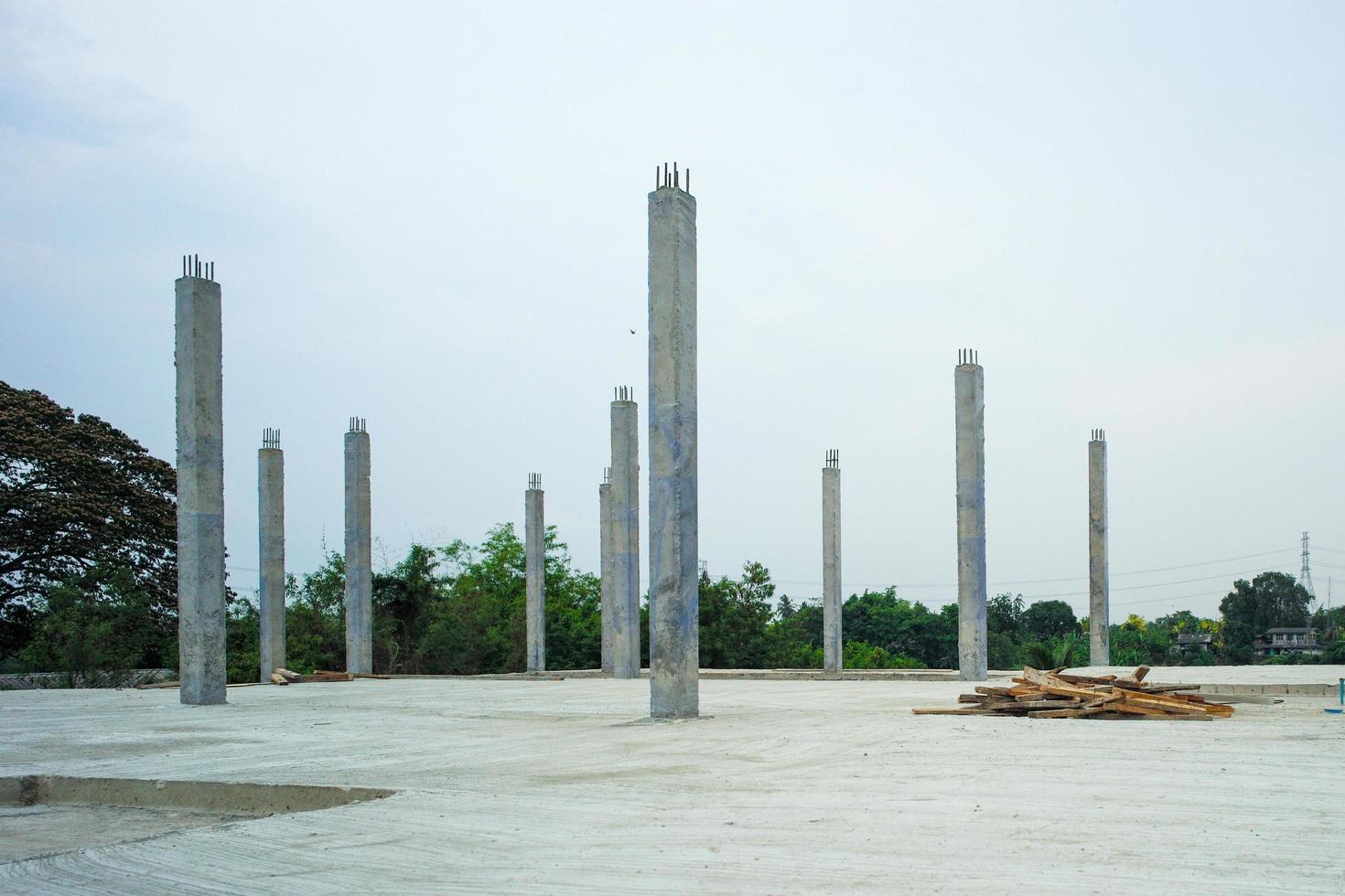 Perspective concrete columns standing on the cement floor at the construction site with clear sky background photo
