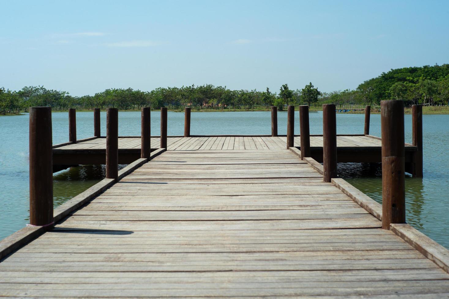 Wooden bridge into the lake with trees and horizontal line in background photo