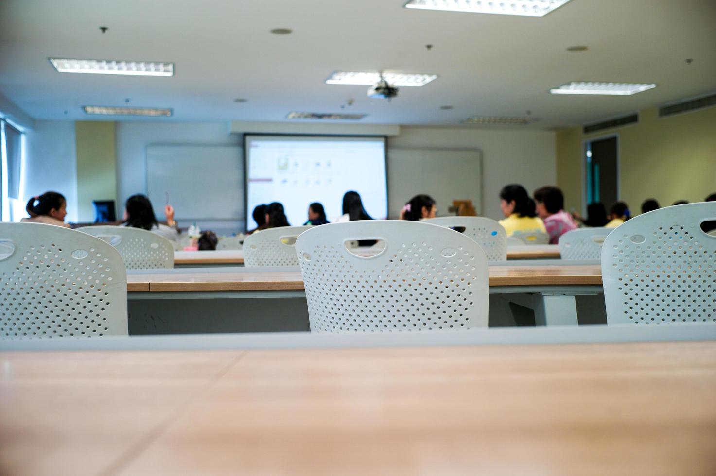 Selective focus on row of empty chairs with blurred group of students in background photo