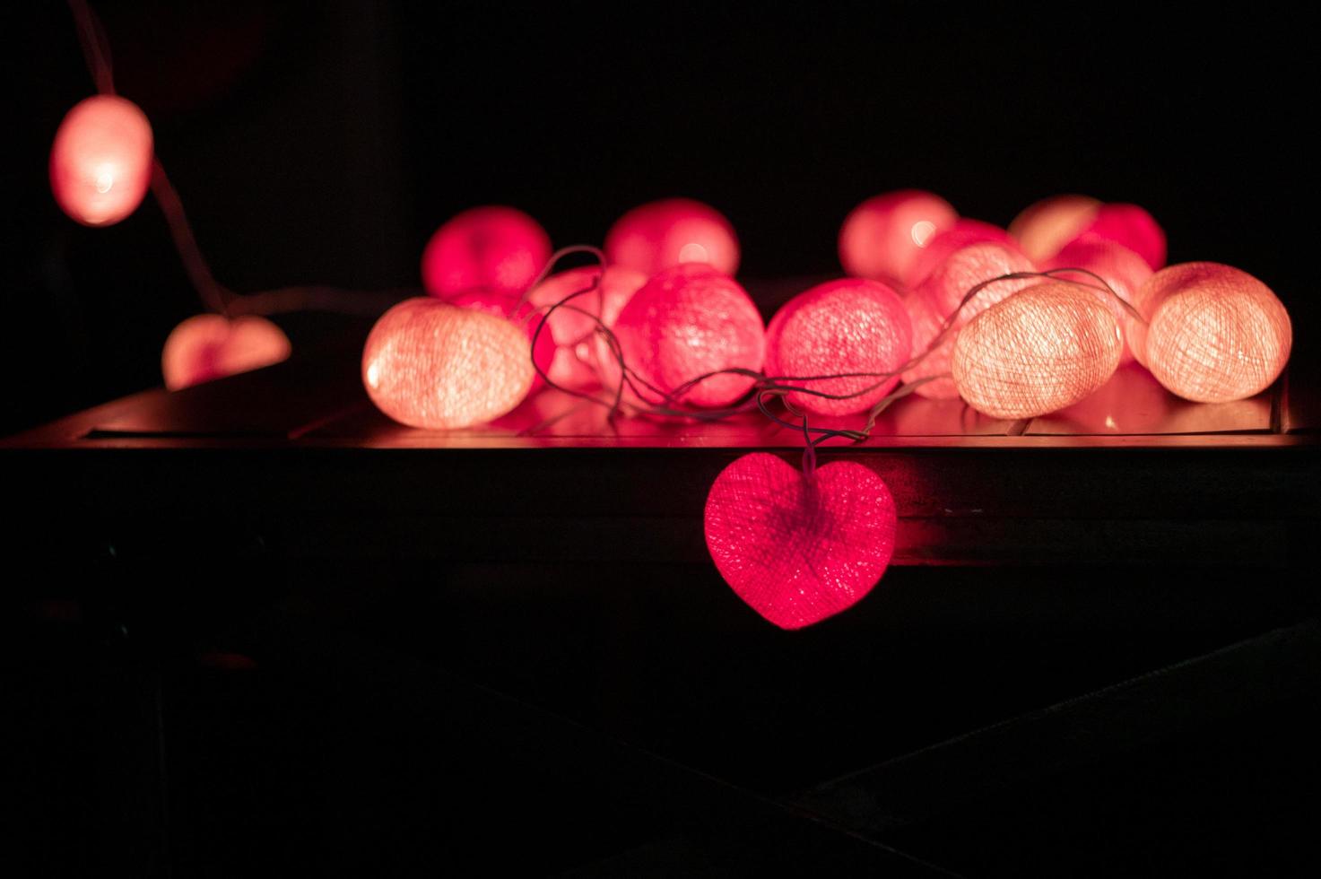 Primer plano de luces LED en forma de corazón decoradas en el cuarto oscuro foto