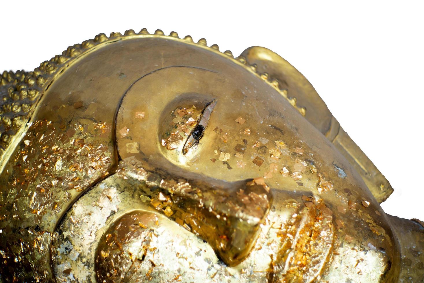 Closeup eye and face of reclining gold Buddha statue coated by the golden leaf isolated on a white background photo