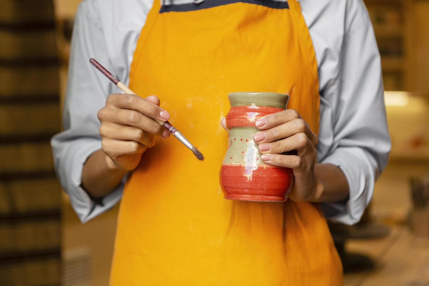 Close-up on an artist holding a clay pot with a brush photo