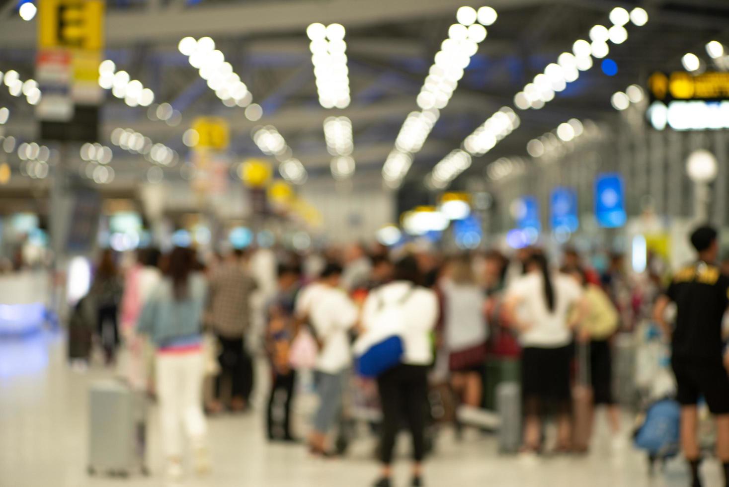 grupo desenfocado de pasajeros que se registran en el mostrador para obtener una tarjeta de embarque en el aeropuerto. imagen borrosa a propósito foto