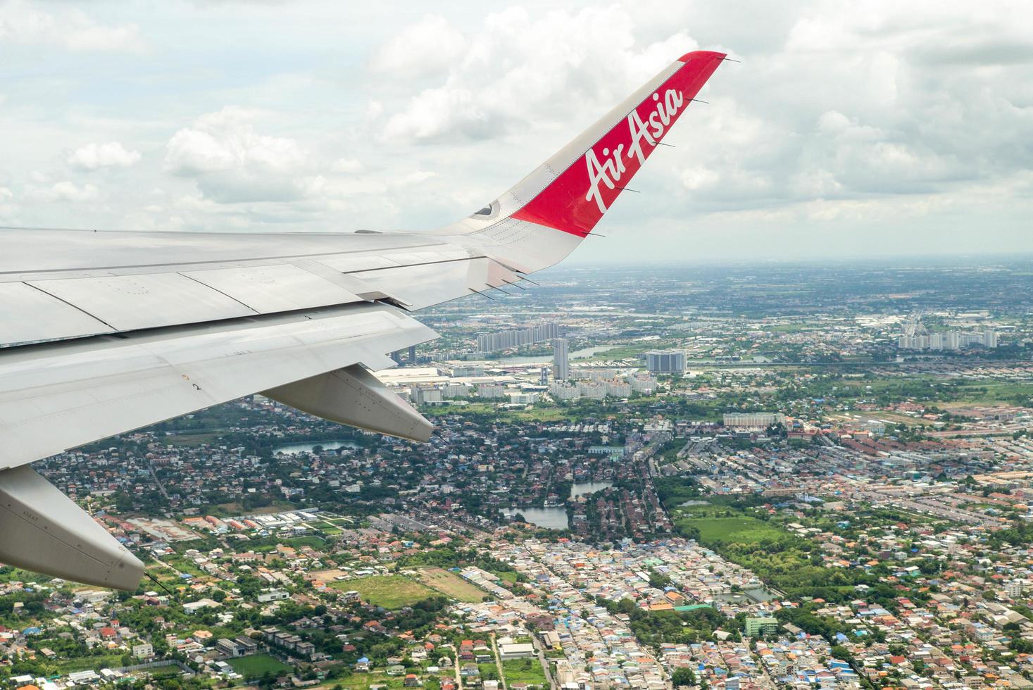 Bangkok, Thailand  - June 8, 2020 - Closeup wing of an Air Asia airplane while flying in the air with cityscape below photo
