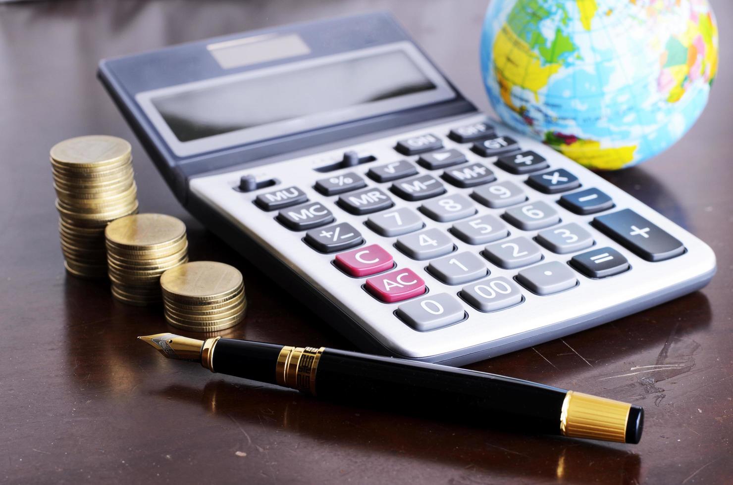Fountain pen and calculator money coins stack and earth for Business concept photo