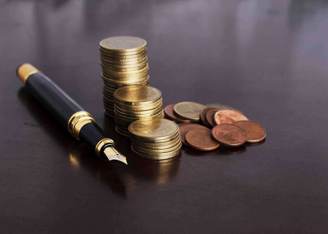 Pila de monedas de dinero y pluma estilográfica para concepto de finanzas foto