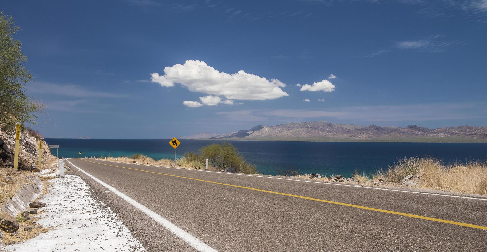 Carretera de Loreto a Santa Rosalia en el estado de Baja California Sur México cerca de Punta Armenta en la Región de Bahía Concepción con el mar de Cortés y cielo azul con nubes y montañas foto