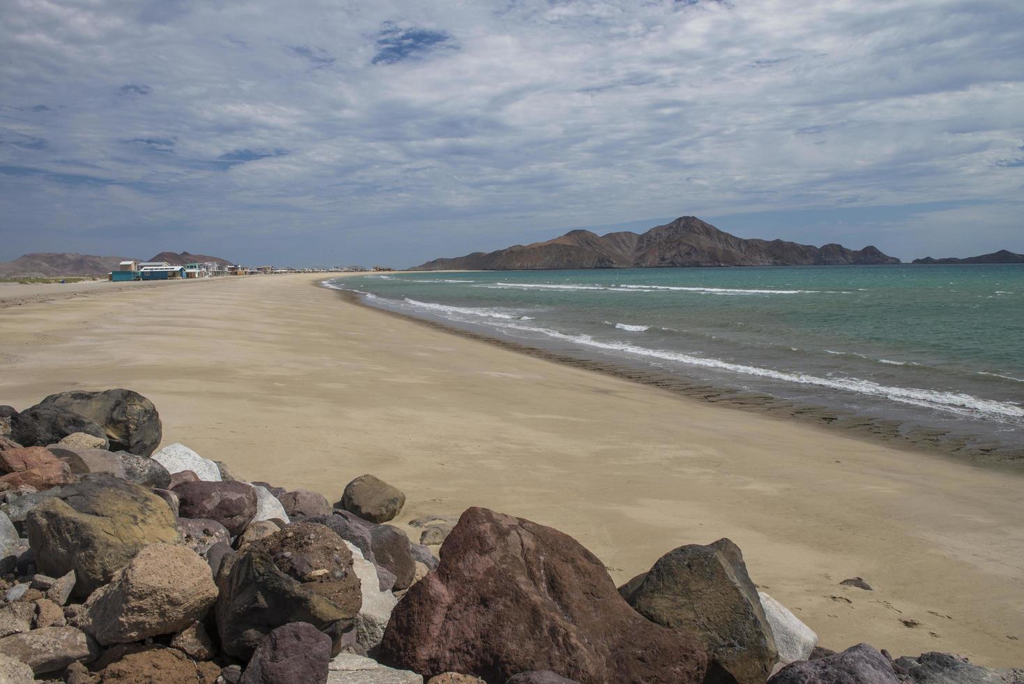 San Luis Gonzaga, Baja California, México con montañas y cielo nublado en el fondo rocas en la playa. foto